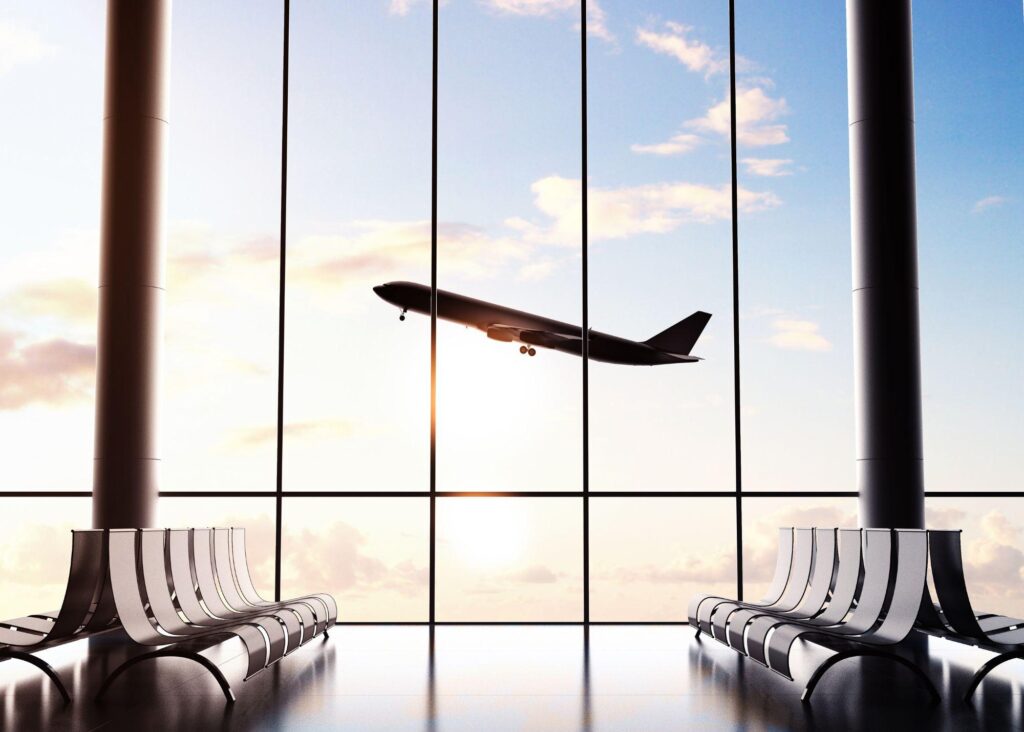 An airport window view of a plane taking off