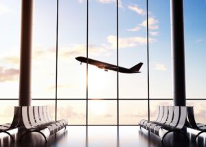 An airport window view of a plane taking off